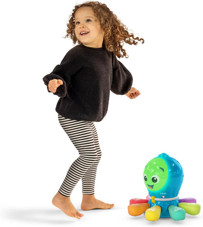 Dziewczynka w czarnej koszulce stojąca przy ośmiornicy Baby Einstein Ocean Explorers z kolorowymi ramionami.