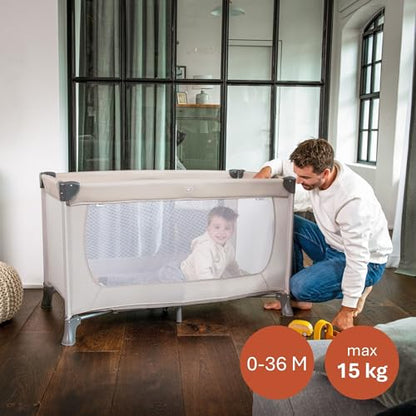 Dziecko w beżowym łóżeczku Hauck Dream N Play, z mężczyzną stojącym obok.